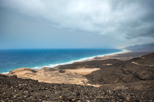 Cofete town and beach in Fuerteventura. beautiful long yellow sand wild beach with with mountains.  blue ocean and clouds on sky. Enjoy the world concept