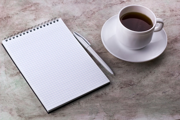 Coffe cup and notebook on a marble background