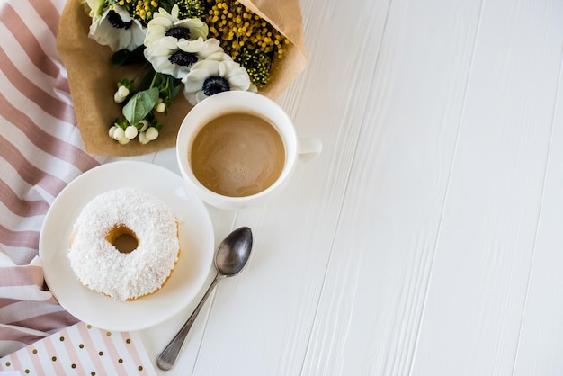 Coffe and a donut with fresh flowers