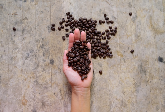 Coffee bean in hand on old wood 