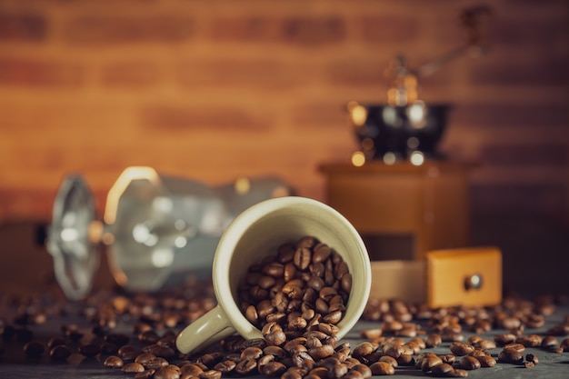 Coffee bean in the white cup and coffee grinder on wooden table. breakfast or coffee time in morning.