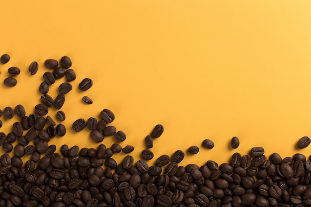 Coffee beans are scattered on a yellow paper  close-up, , commercial copyspace.