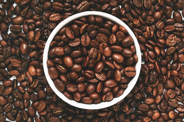 Coffee beans in a bowl over coffee beans background flat lay