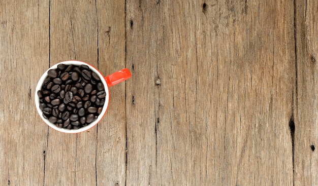 Coffee beans in ceramic cup on old wood desk at kitchen room