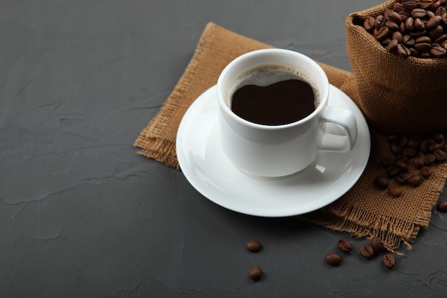 Coffee beans and coffee cup on colored background with place for text