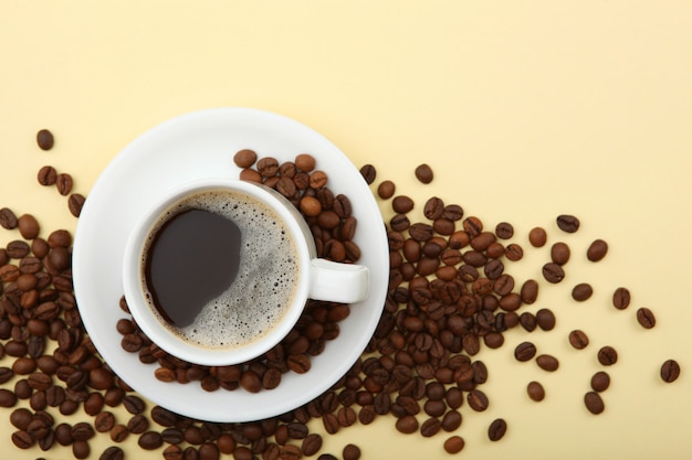 Coffee beans and coffee cup on colored background with place for text