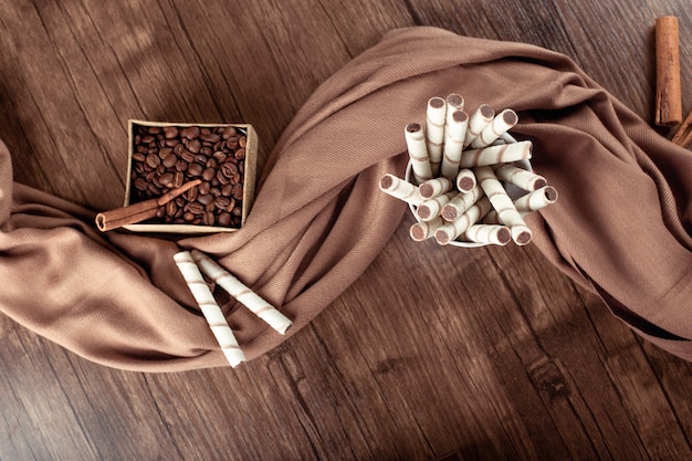 Coffee beans and connamons on box on wooden table on brown scarf