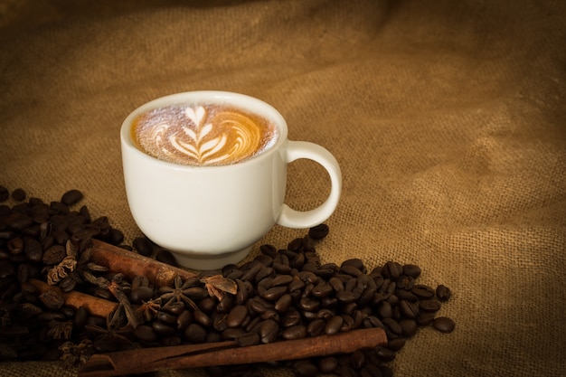 Coffee beans and cup coffee on the cloth sack select focus, Vintage color tone or dark tone