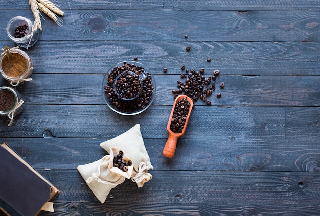 Coffee beans and cup of coffee with other components on different wooden background. 