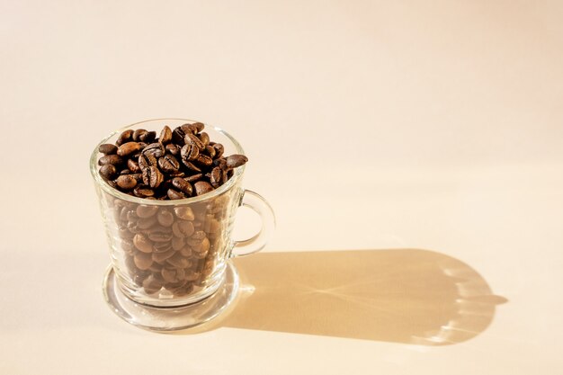 Coffee beans in a glass cup on a light background