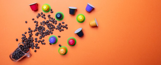 Coffee beans and a glass cup on orange color background copy space