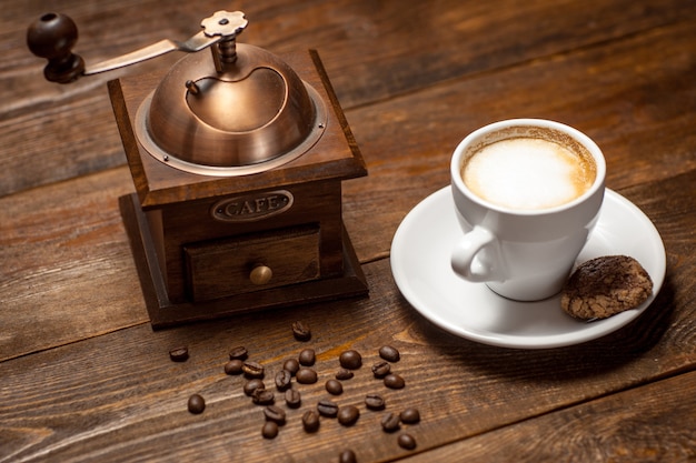 Coffee beans grinder cappuccino cup on wooden table