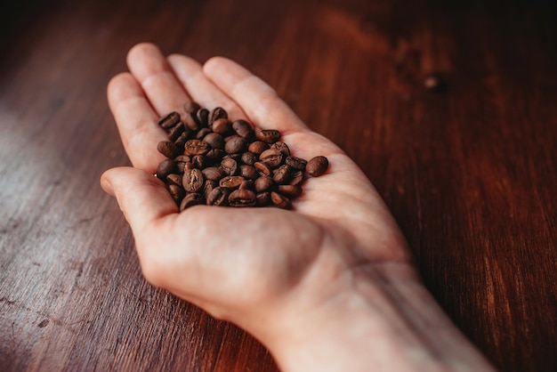 coffee beans in a hand on the wooden background