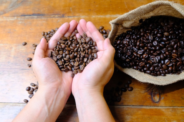 Coffee beans in hands with a coffee bag and a cup of coffee latte