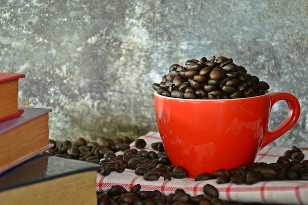 Coffee beans in red ceramic cup on old wood desk