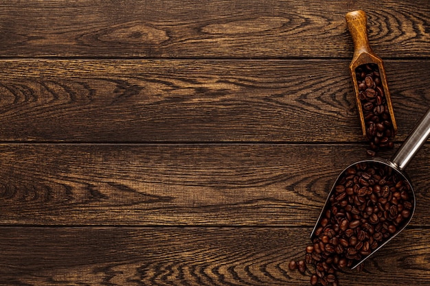 Coffee beans in scoop over wooden background wood board texture with roasted grains portion in vinta