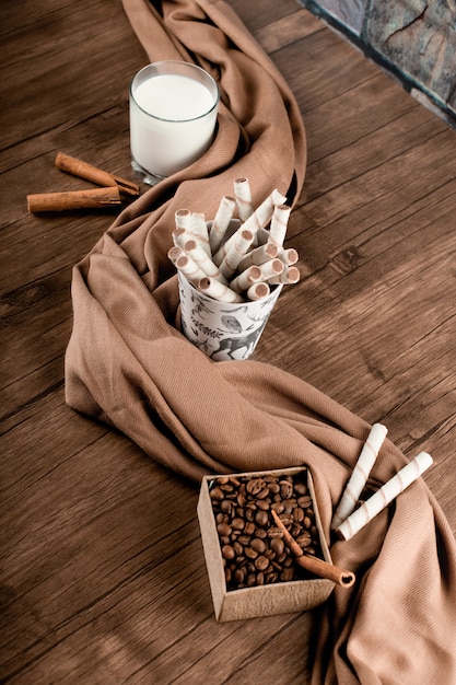 Coffee beans, waffle sticks and a glass of milk wrapped with a scarf. top view