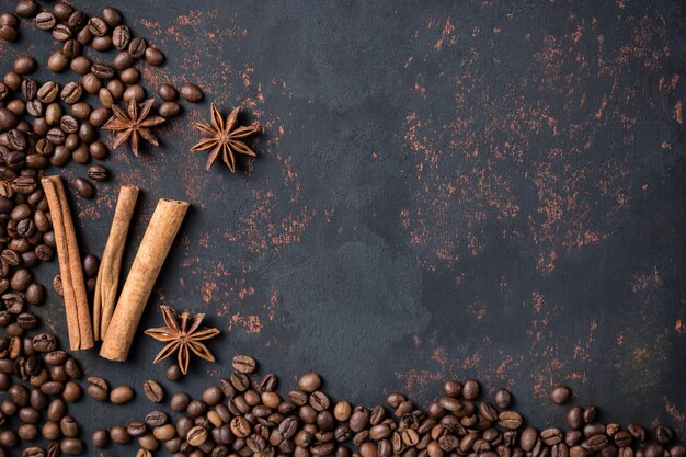 Coffee beans with spices anise and cinnamon sticks on rusty stone surface background