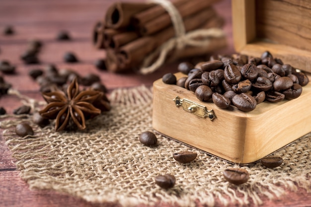 Coffee beans in a wooden box with cinnamon sticks and star anise on burlap napkins