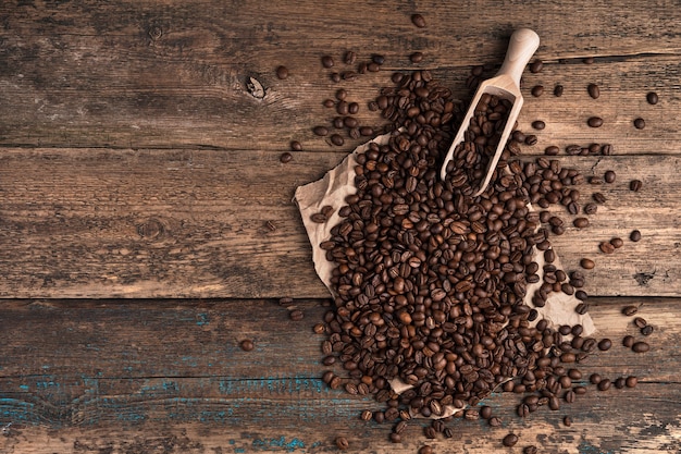 Coffee beans and a wooden spatula on a wooden surface