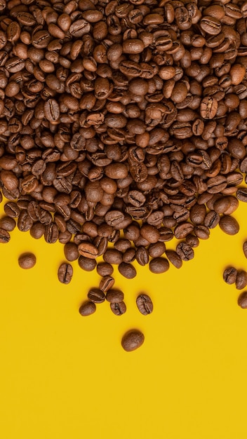 Coffee beans on a yellow background, other grains scattered around, concept