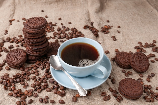 Coffee in a blue cup. Nearby chocolate chip cookies.