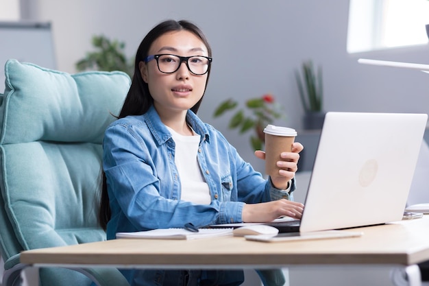 Coffee break in the office young beautiful asian business woman holding a cup of coffee drinking