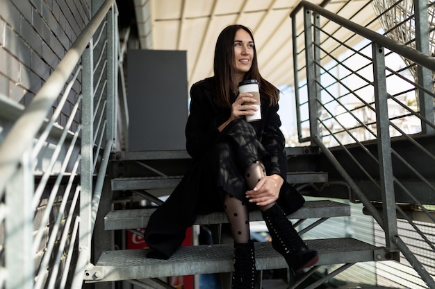 Coffee break of a young adult on the steps of a business center