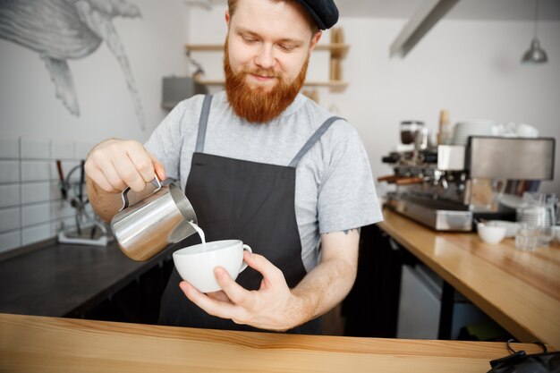 Coffee Business Concept - handsome bearded man in apron making coffee while standing at cafe