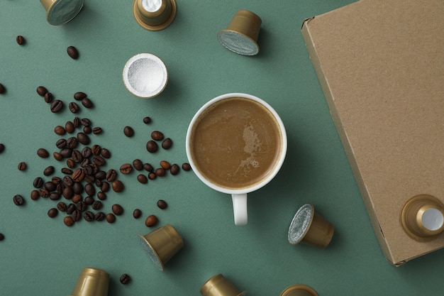 Coffee capsules beans cup with coffee drink and box on green background top view