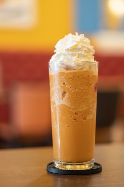 Coffee caramel frappe with whipped cream on wood table