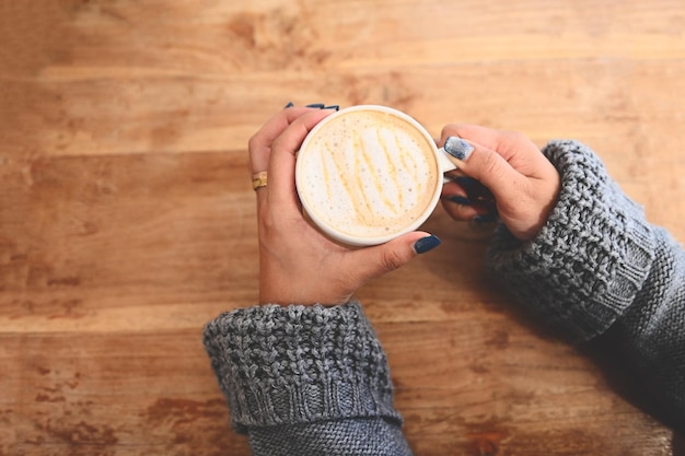 Coffee caramel woman coffee with hand holding a cup on the wood table caramel coffee cup in the morning hot caramel macchiato