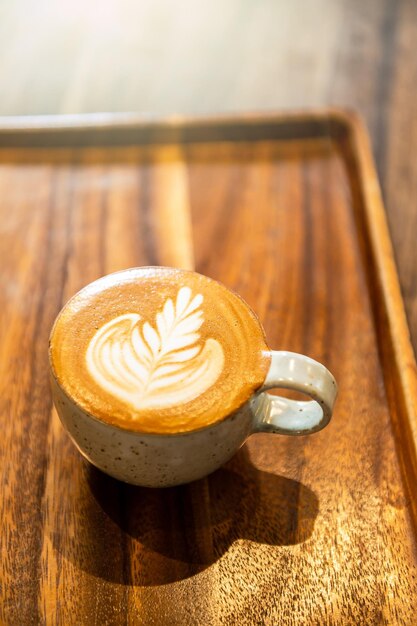 Coffee in ceramic cup on wooden table in cafe with lighting background