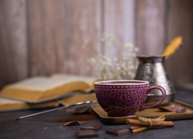 coffee and cinnamon on dark table with open books and wooden walls