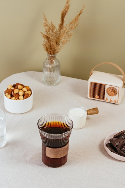 Coffee in a clear glass on the table milk in a milk jug chocolate in a plate