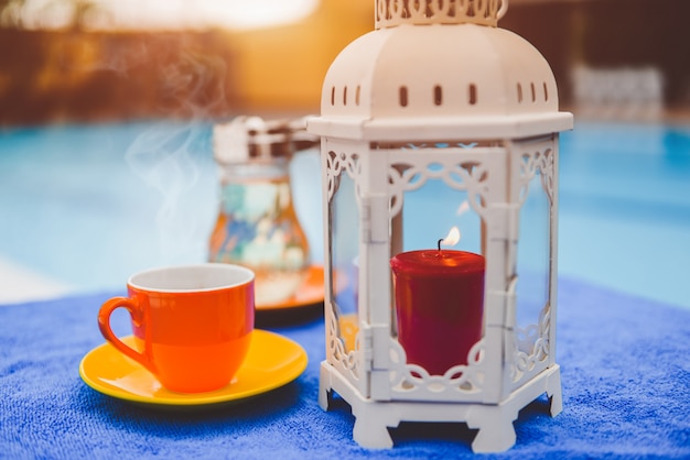 Coffee cup and candle by hotel swimming pool