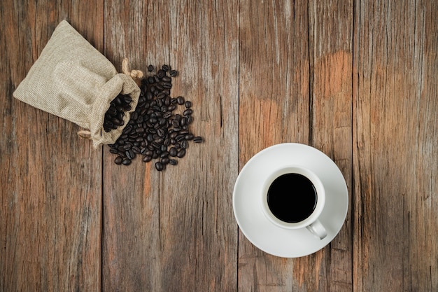 Photo coffee cup and coffee beans bag on rustic wooden texture table in top view with copyspace 