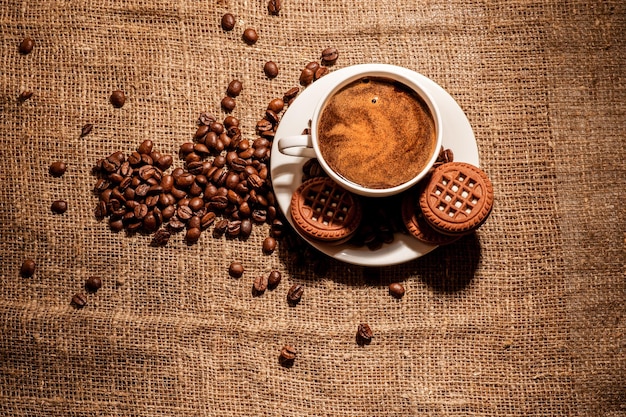 Coffee cup and coffee beans on wooden table and sack background Vintage color tone