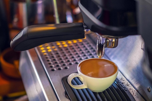 Coffee cup of espresso pouring from the coffee machine Professional coffee brewing in the cafe