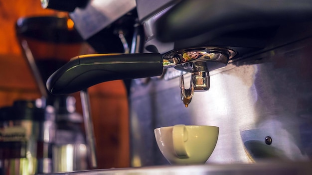 Coffee cup of espresso pouring from the coffee machine Professional coffee brewing in the cafe