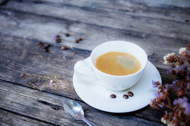 Coffee cup and flower on table.