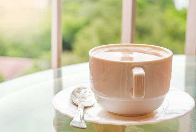 Coffee in a cup on a glass table, a balcony with a view of nature and the sea, a delicious breakfast at sunrise.