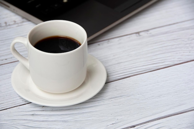 Coffee cup and laptop on wooden table with customizable space for text or ideas Copy space