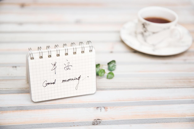 Coffee cup and notepad on white desktop