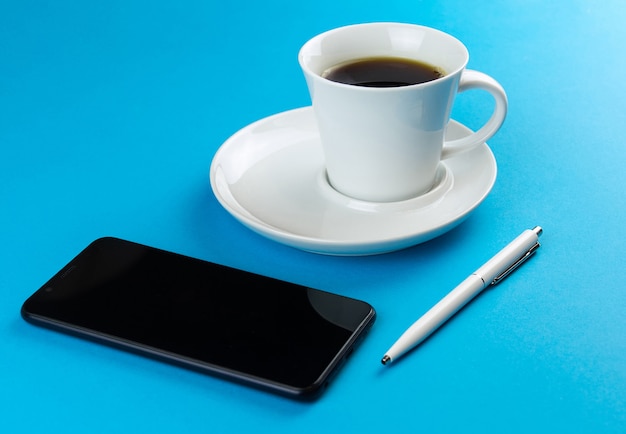 Coffee Cup smartphone and white pen on a blue background