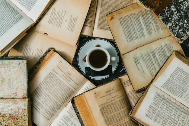 Coffee cup surrounded by open antique books