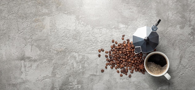 Coffee cup on table cloth coffee beans and mocha pot on concrete background