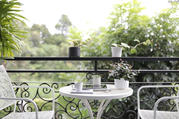 Photo coffee cup and and tablet and plant pot on white metal table at balcony outdoor