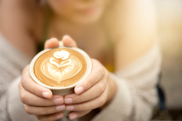 Coffee cup top view of woman hands. Coffee latte art in morning concept.