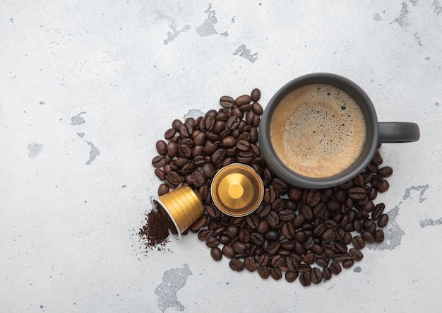 Coffee cup with fresh beans and ground coffee capsules on light kitchen background